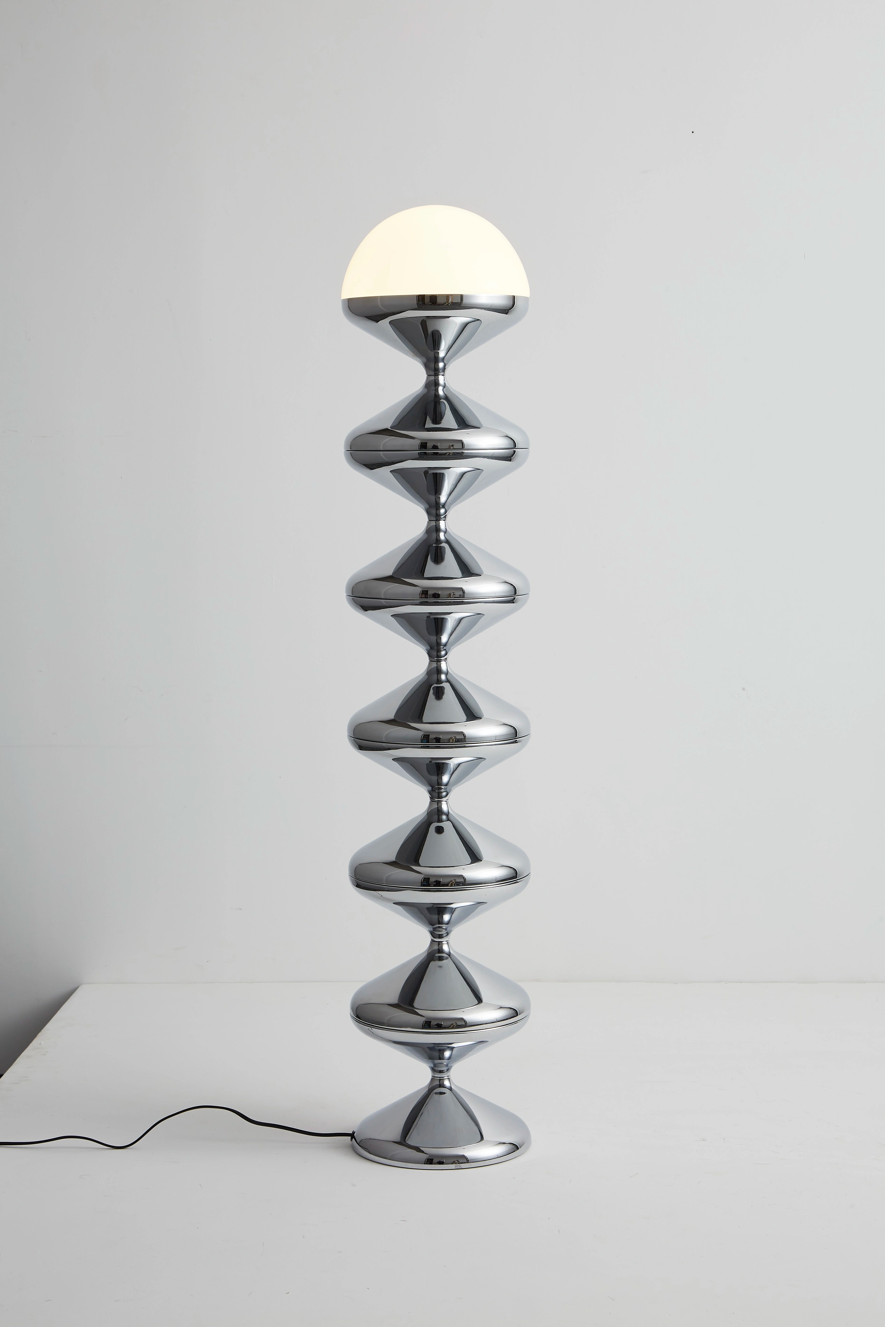 Sleek modern chrome lamp with a sculptural stacked hourglass design and a rounded white shade for elegant living room lighting.