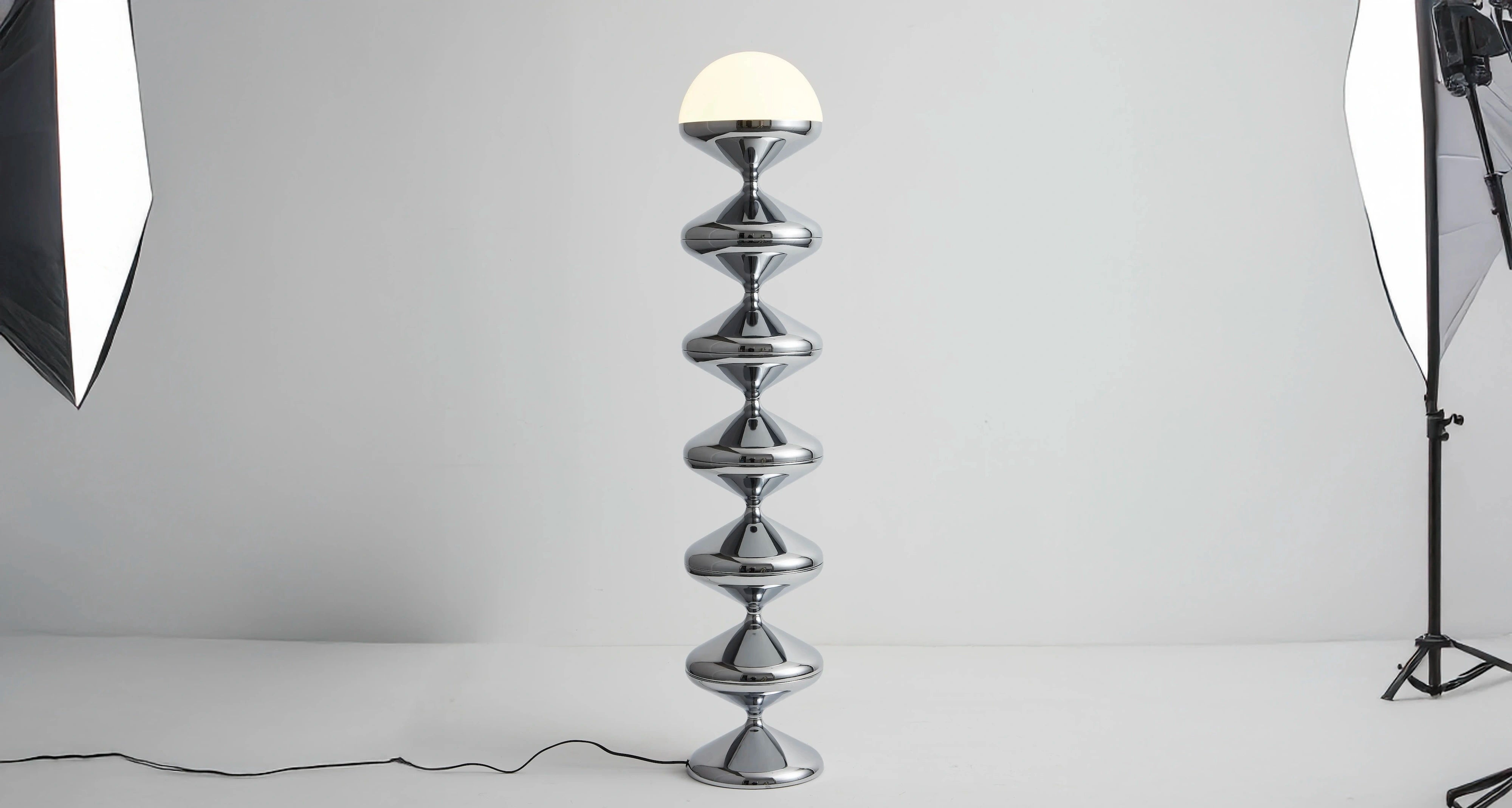 Sleek chrome floor lamp with a unique stacked hourglass design and round white shade ideal for modern living room accent lighting.