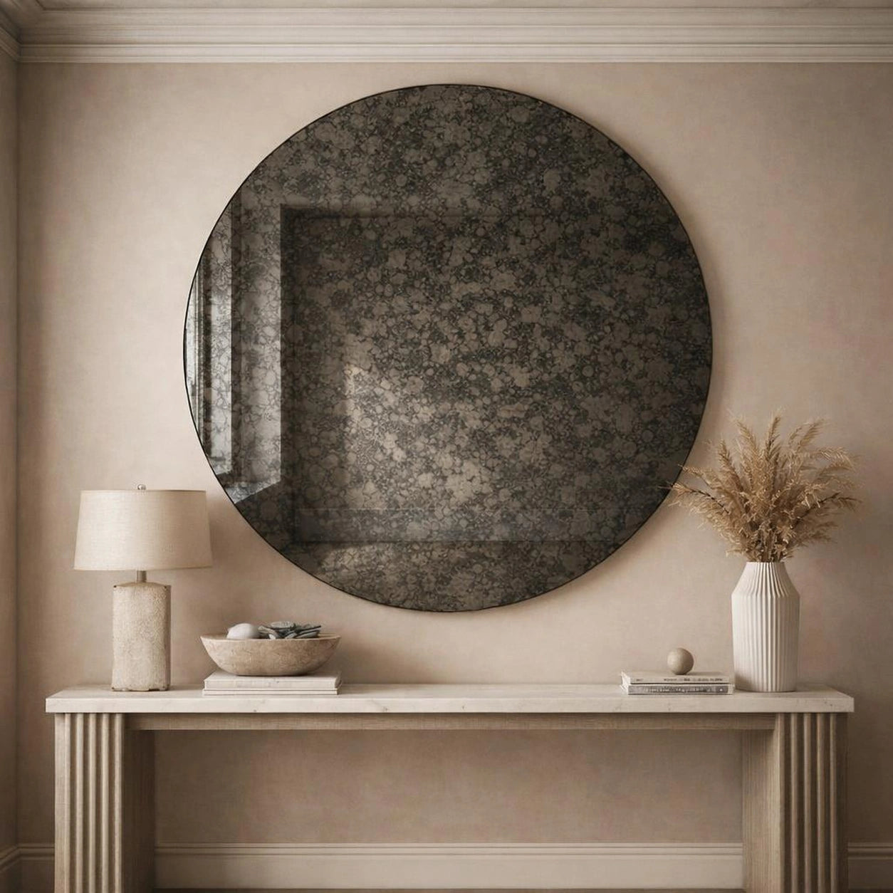 Charcoal antiqued round mirror hung above a console table in a neutral entryway