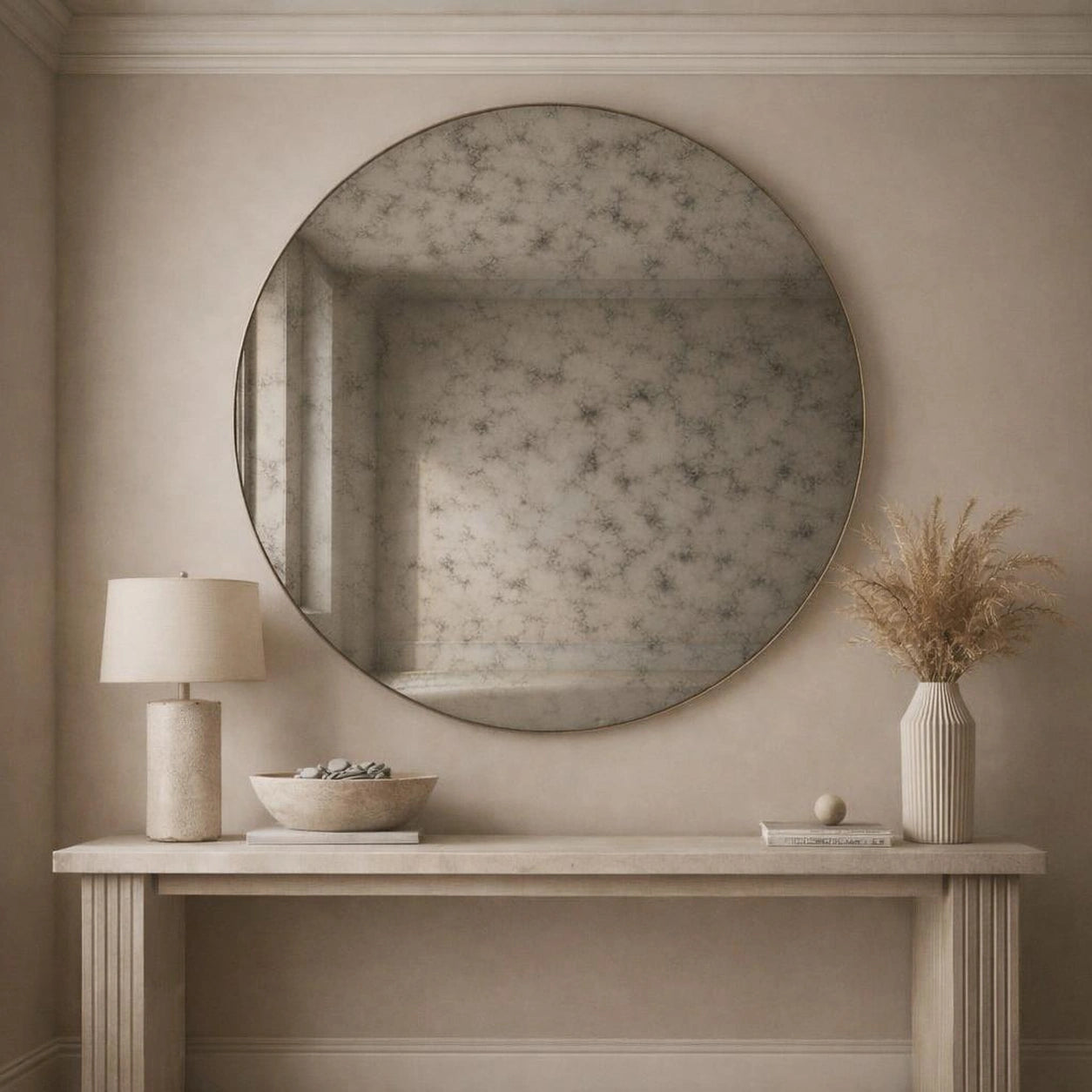 Smoked antiqued round mirror hung above a console table in a neutral entryway