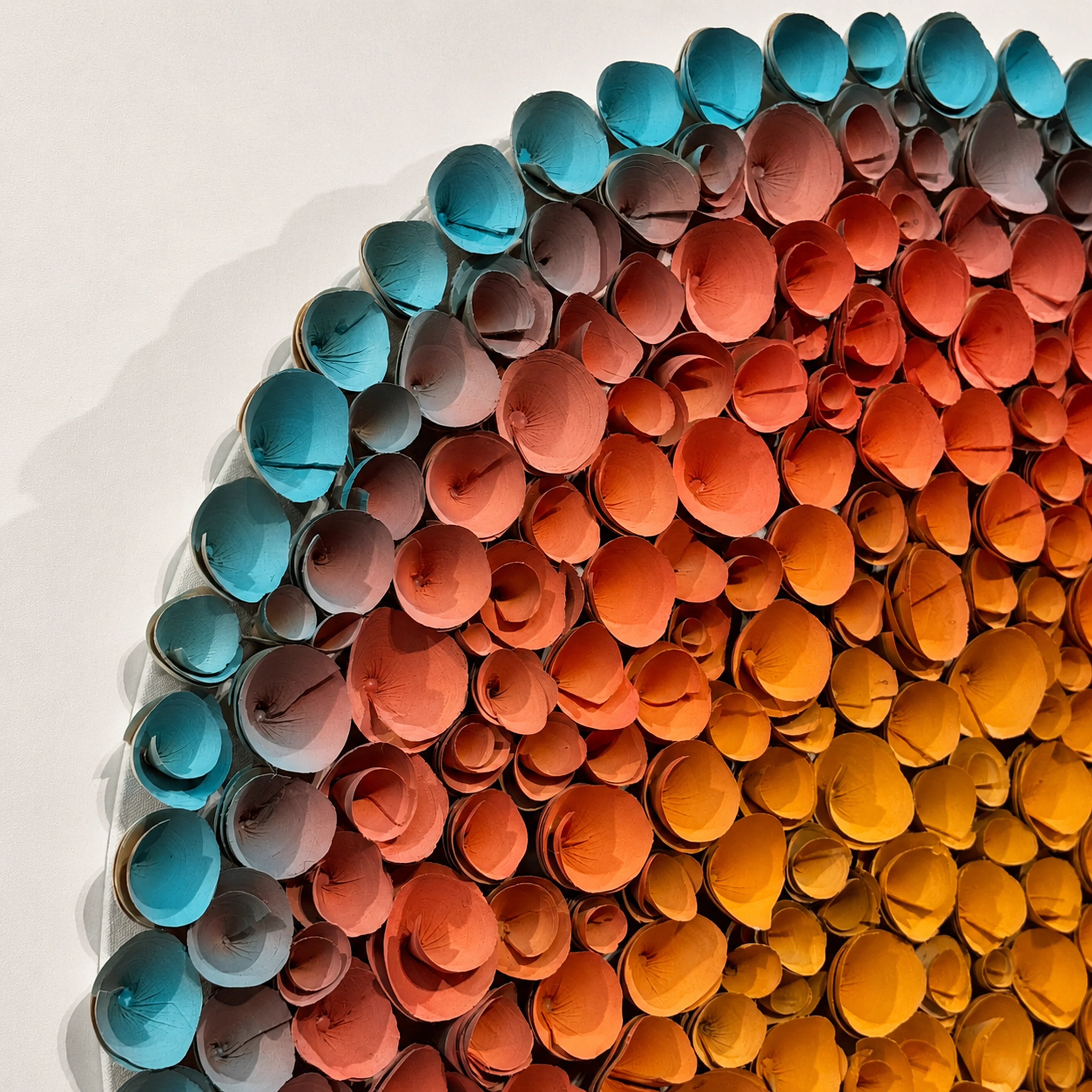 Close detail of hand-rolled paper coils in Coronal Bloom — orange to blue gradient relief