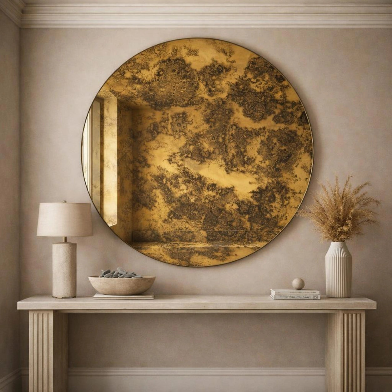 Gold antiqued round mirror hung above a console table in a neutral entryway