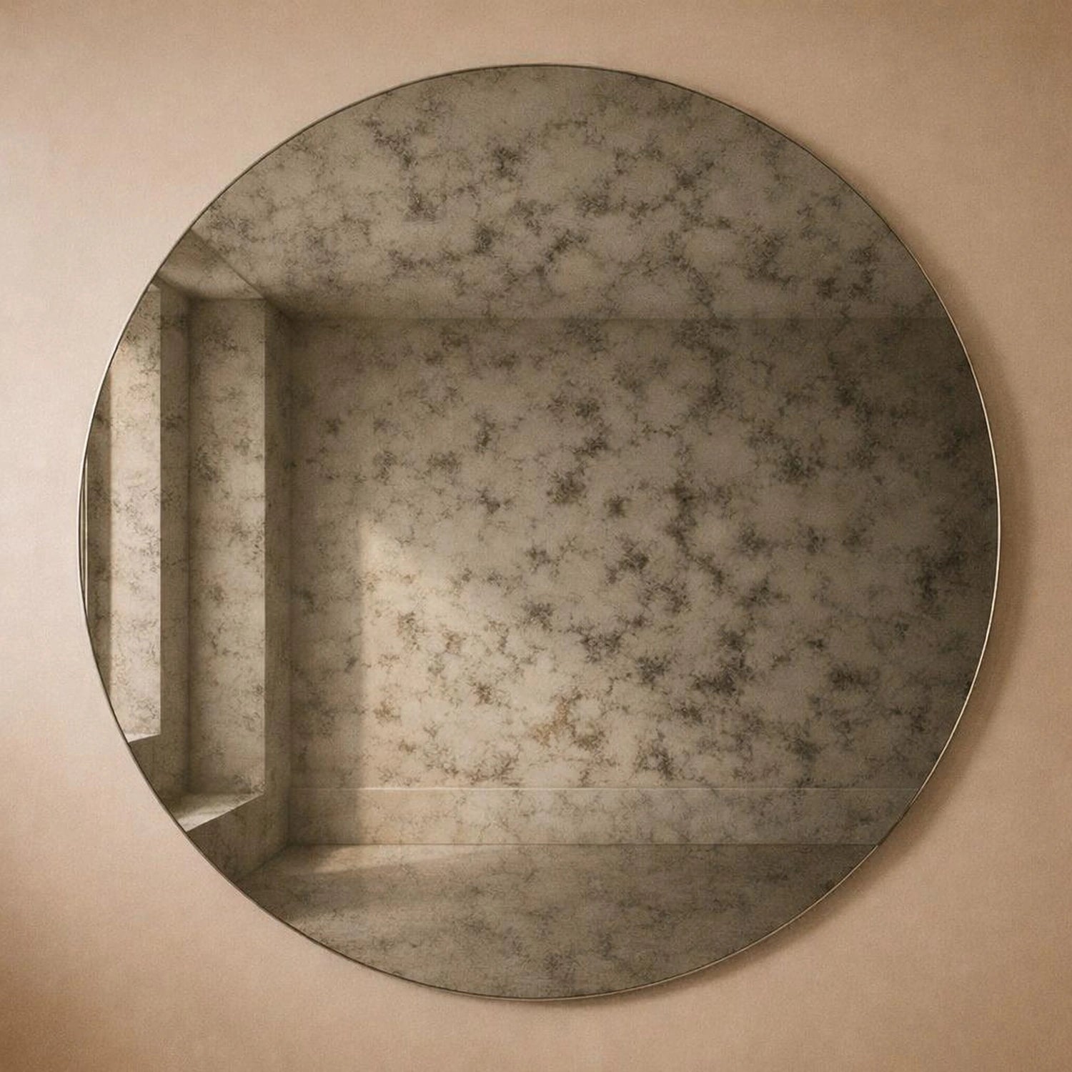 Smoked antiqued round wall mirror with light-to-dark foxing on a warm wall, full frame