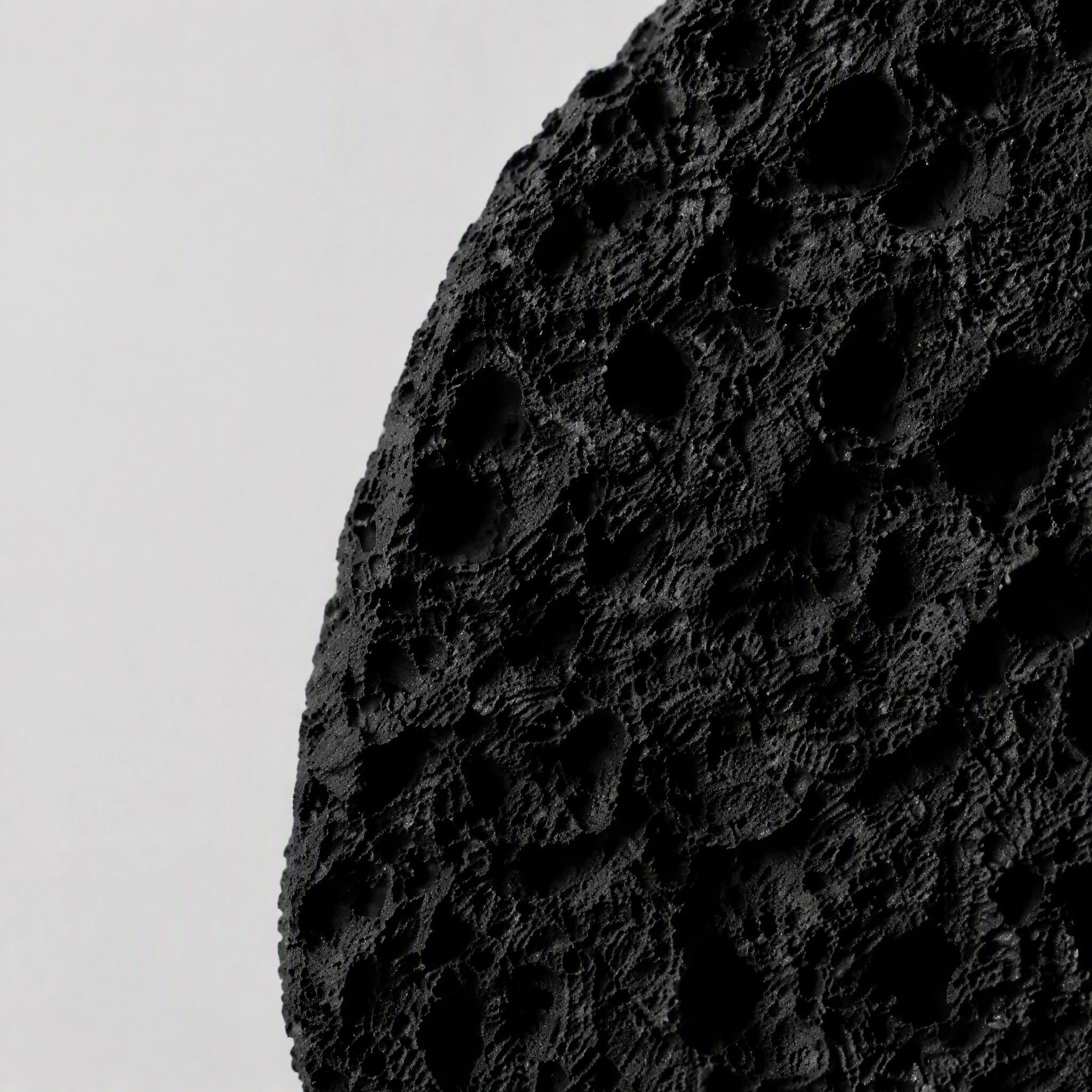 Close material detail of the matte black edge and eroded surface relief
